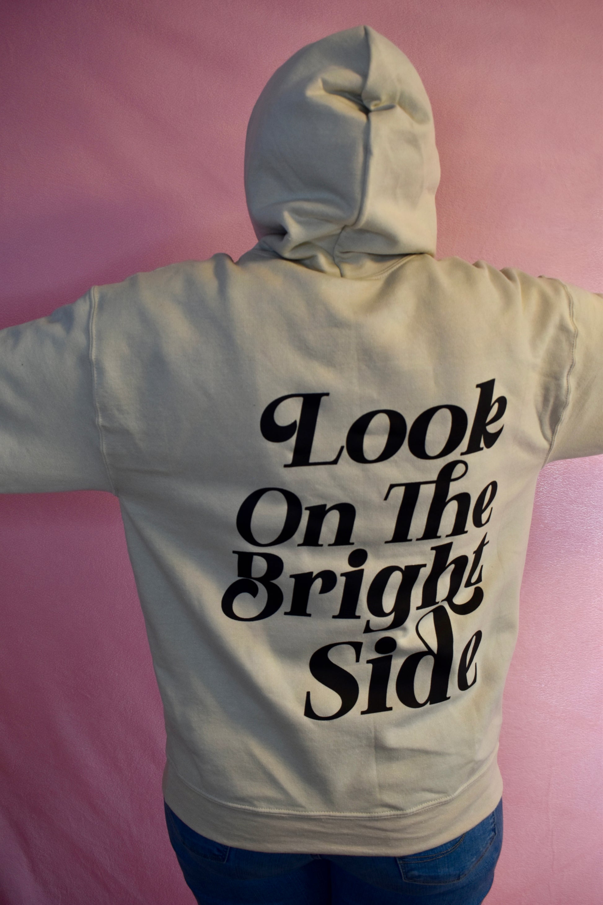 Woman wearing a beige hoodie printed with the words Look On The Bright Side