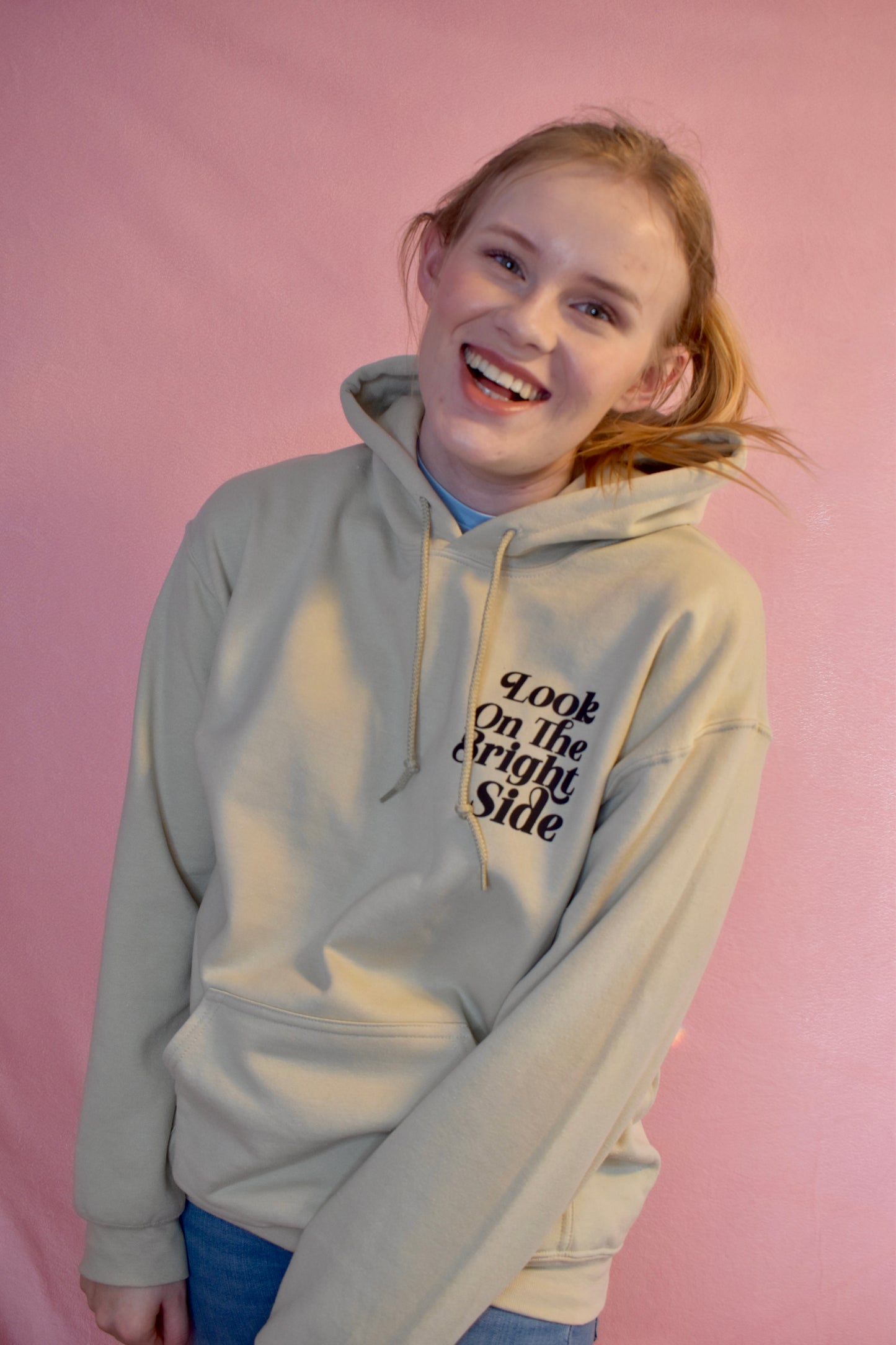 Woman wearing a beige hoodie printed with the words Look On The Bright Side