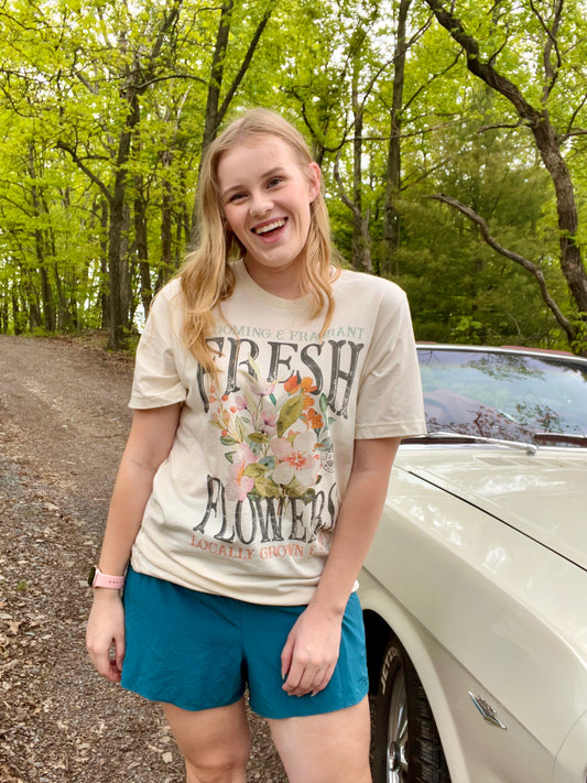 Woman modeling a vintage oversized beige graphic tee with a design featuring the words "Fresh Flowers" and a design of flowers