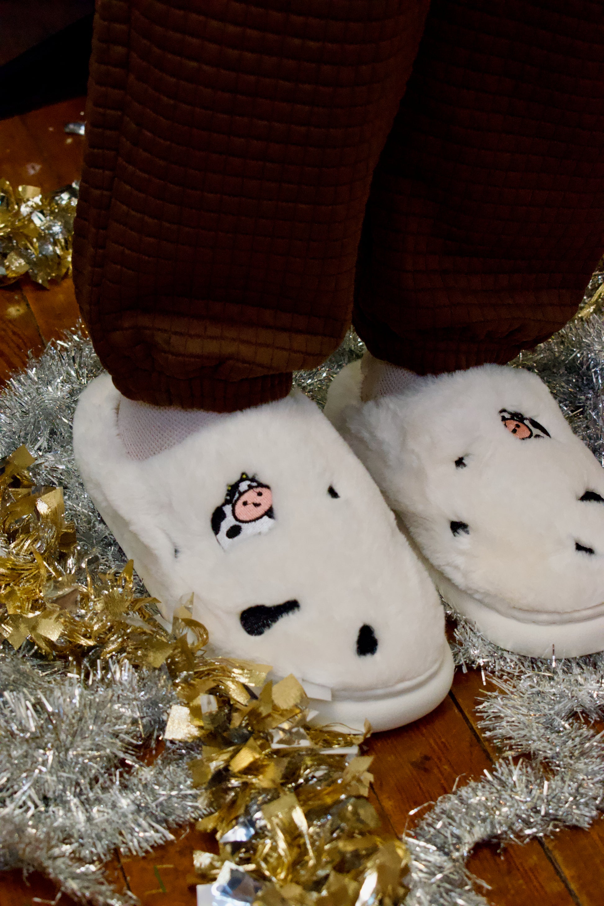 Model wearing white slippers with cow embroidery