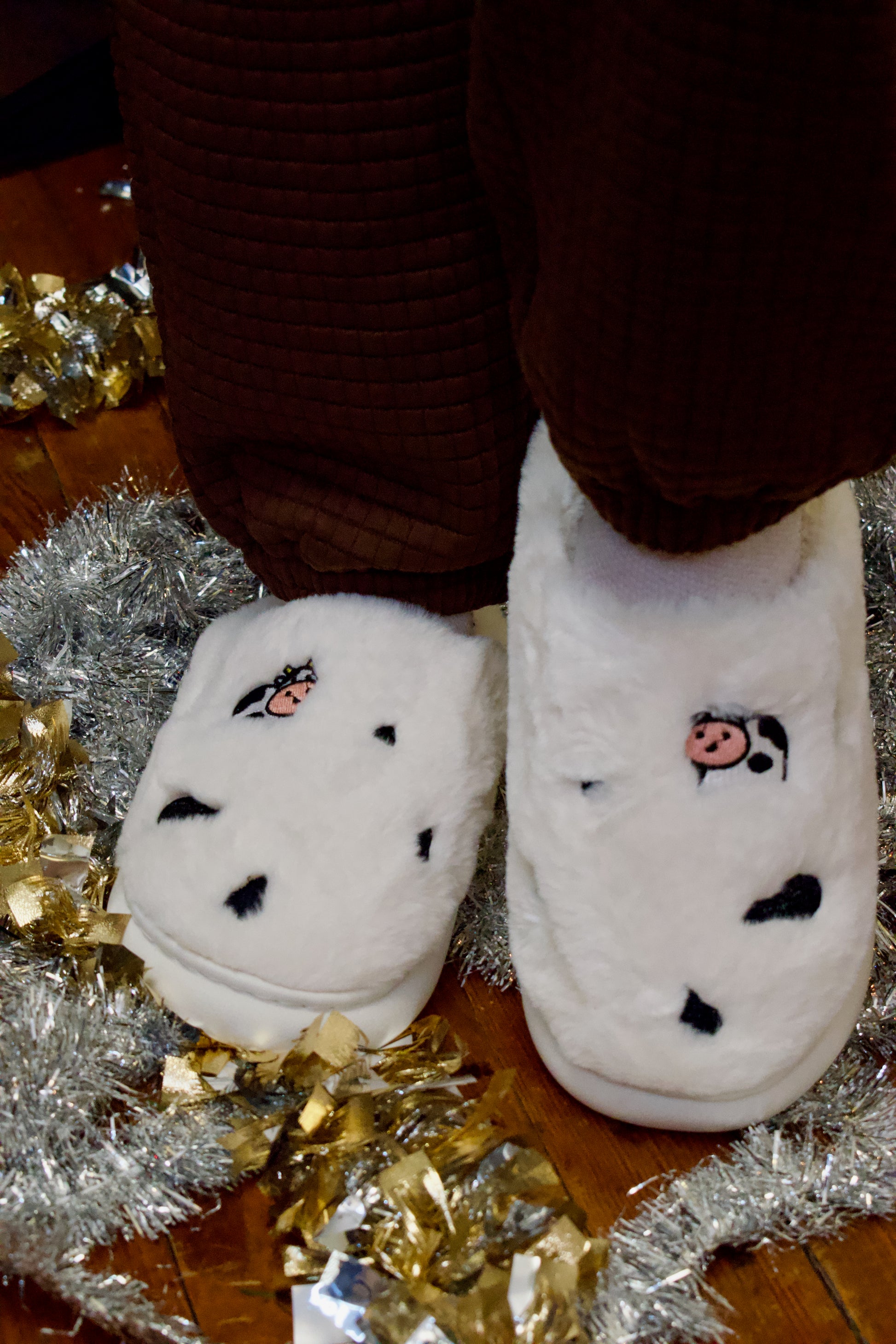 Model wearing white slippers with cow embroidery