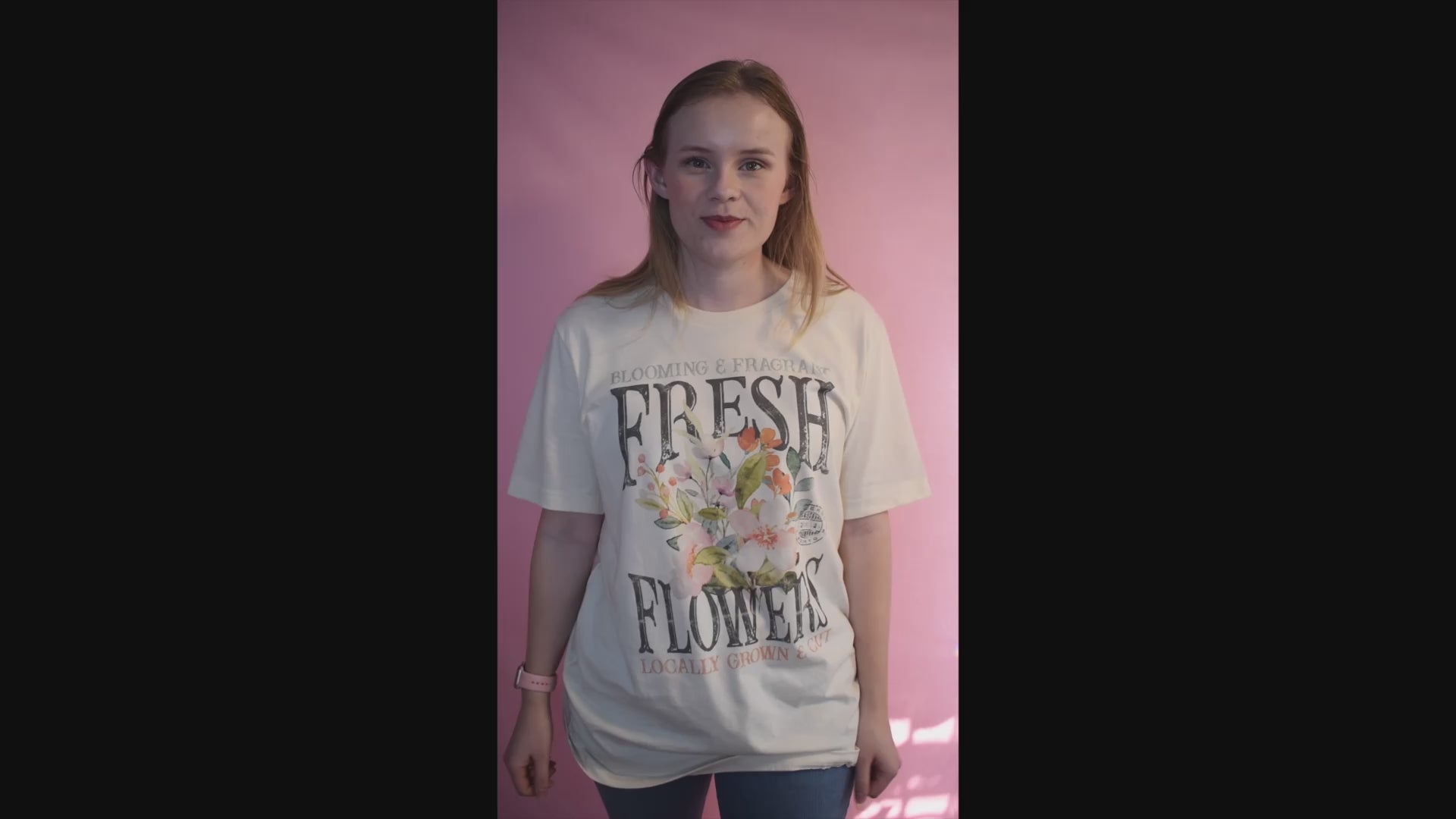 Short Video of a woman wearing a beige tee with a fresh flowers design on it. She is explaining how it is oversized and perfect for spring